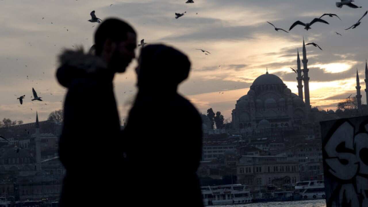 A couple hug each other in front of the Suleymaniye Mosque during a sunset in Istanbul, Turkey