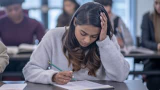 A university student has her head in her hand on desk