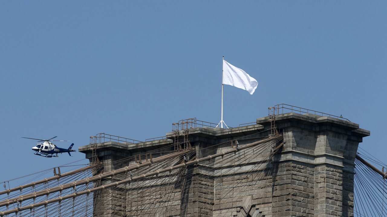 An NYPD helicopter flies over the Brooklyn Bridge inspecting white flags that have been placed on the top, Brooklyn, New York, USA, 22 July 2014. Police are investigating who removed the American Flags and changed them overnight. (EPA)