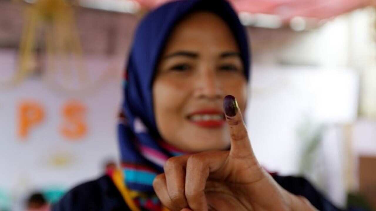 An Indonesian woman shows her ink-stained finger after casting her vote during regional elections in Tangerang.