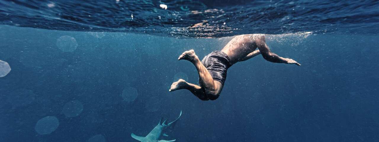 Man swimming by shark in sea