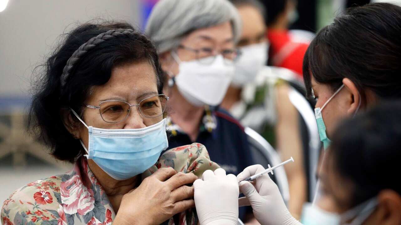 A middle-aged woman wearing glasses and a face mask getting a vaccine