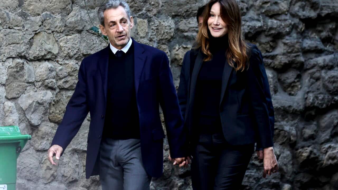 A man and a woman walk, holding hands