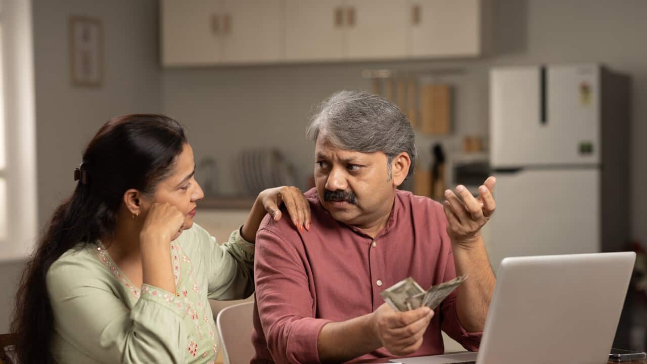 Worried mature couple counting money at white using laptop indoors stock photo