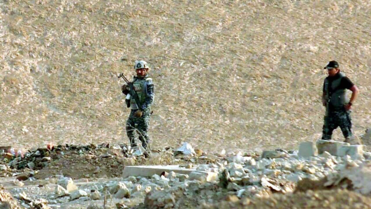 Iraqi police officers at the site of a mass grave near Mosul