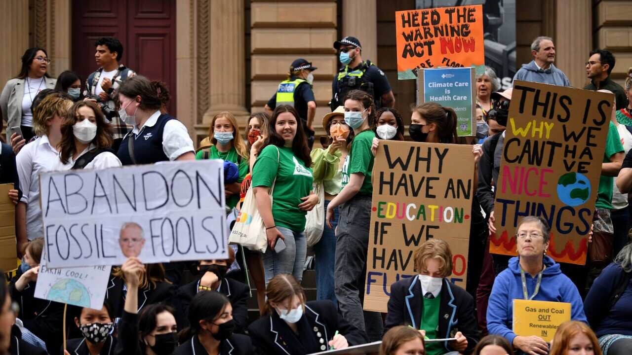 School students hold placards during a Climate School Strike protest at Treasury Gardens in Melbourne, Friday, March 25, 2022. (AAP Image/Joel Carrett) NO ARCHIVING