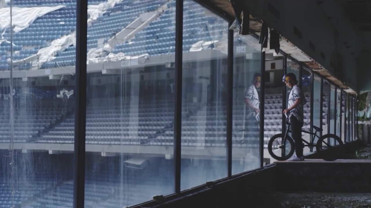 Tyler Fernengel looks out the window of an abandoned stadium with his BMX
