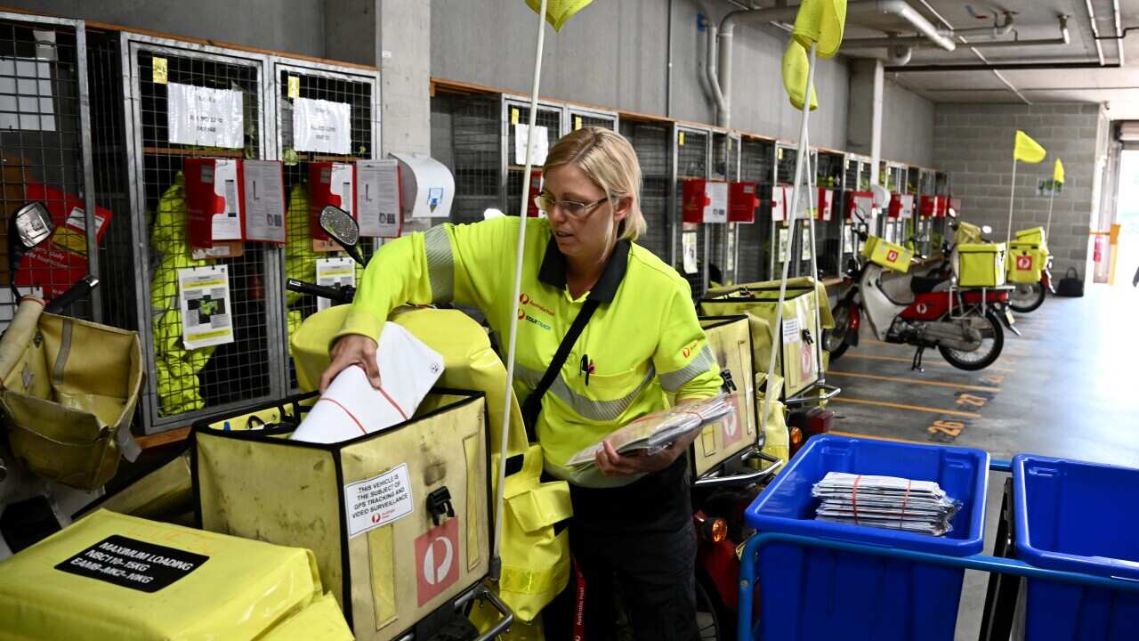 A postal worker loading a satchel with letters ready to take out on a delivery.