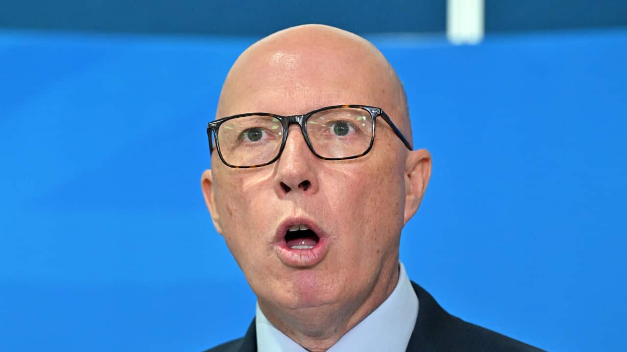 Peter Dutton speaking in front of a blue background