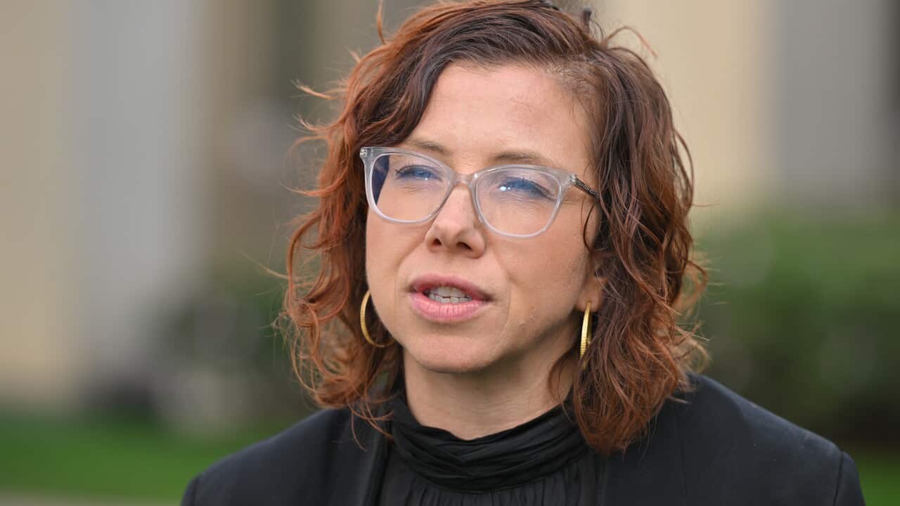 A woman with brown, curly hair wearing glasses