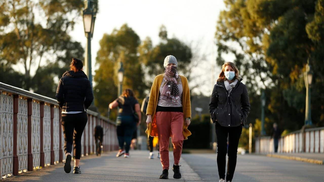 People wearing masks walk along the Morell Bridge in Melbourne, 24 July 2020.