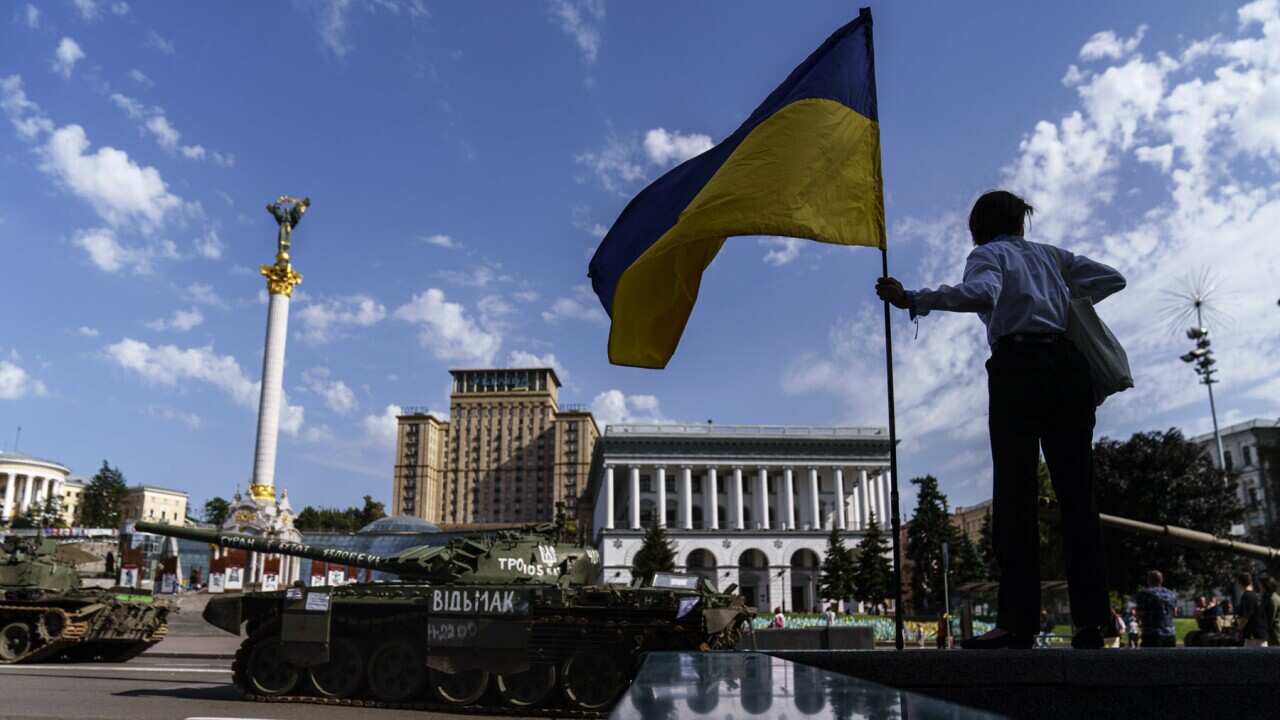 A woman holds a flag of Ukraine in Kyiv (AAP).jpg