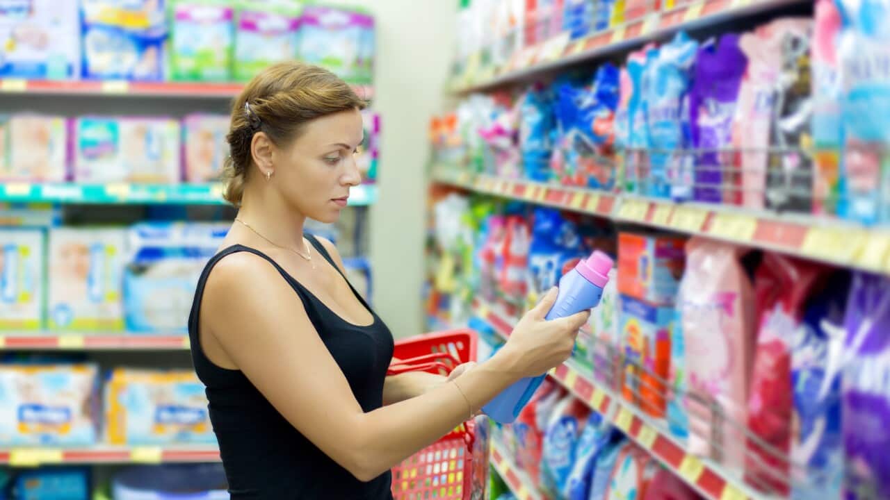 A woman looks at a label while shopping at a supermarket