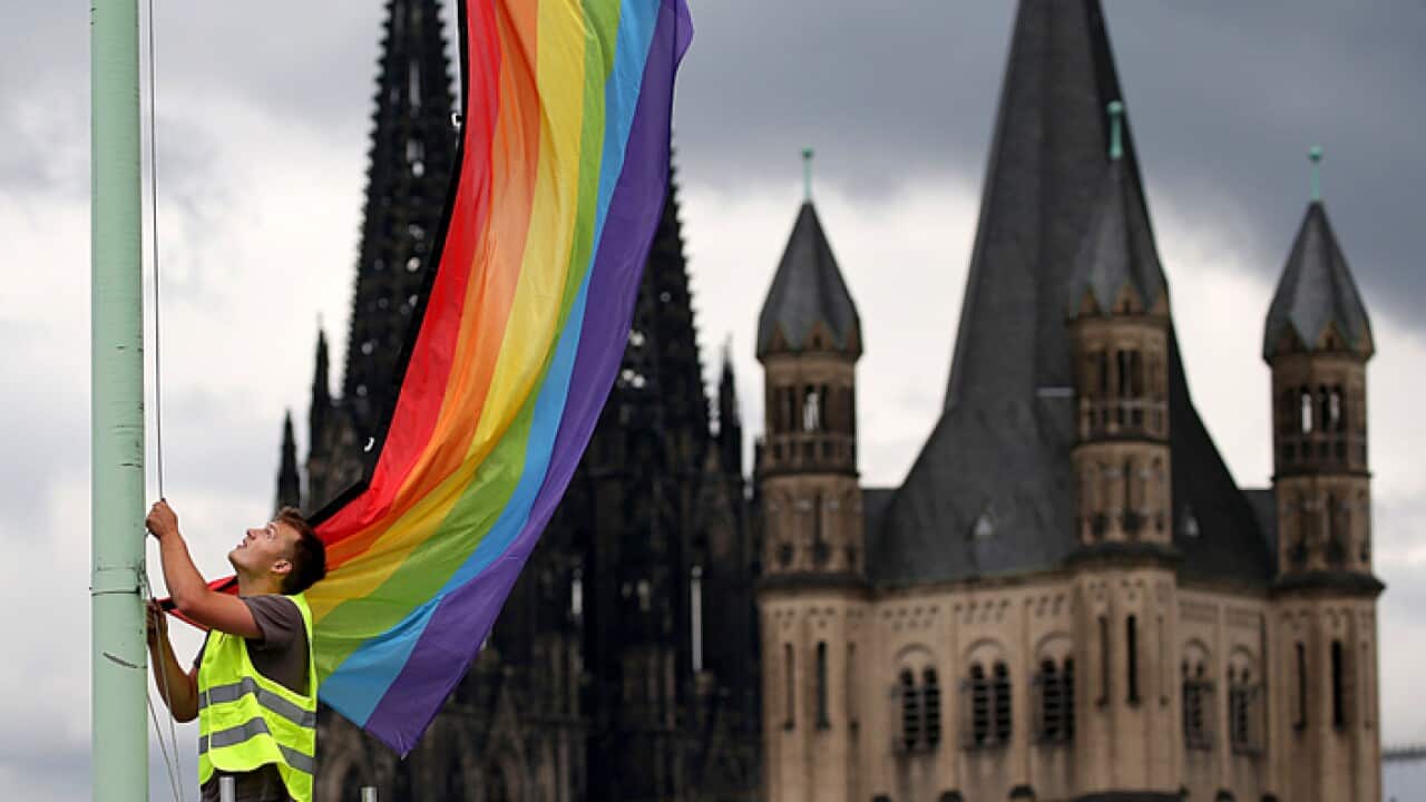 A worker hanging a rainbow flag in Germany.
