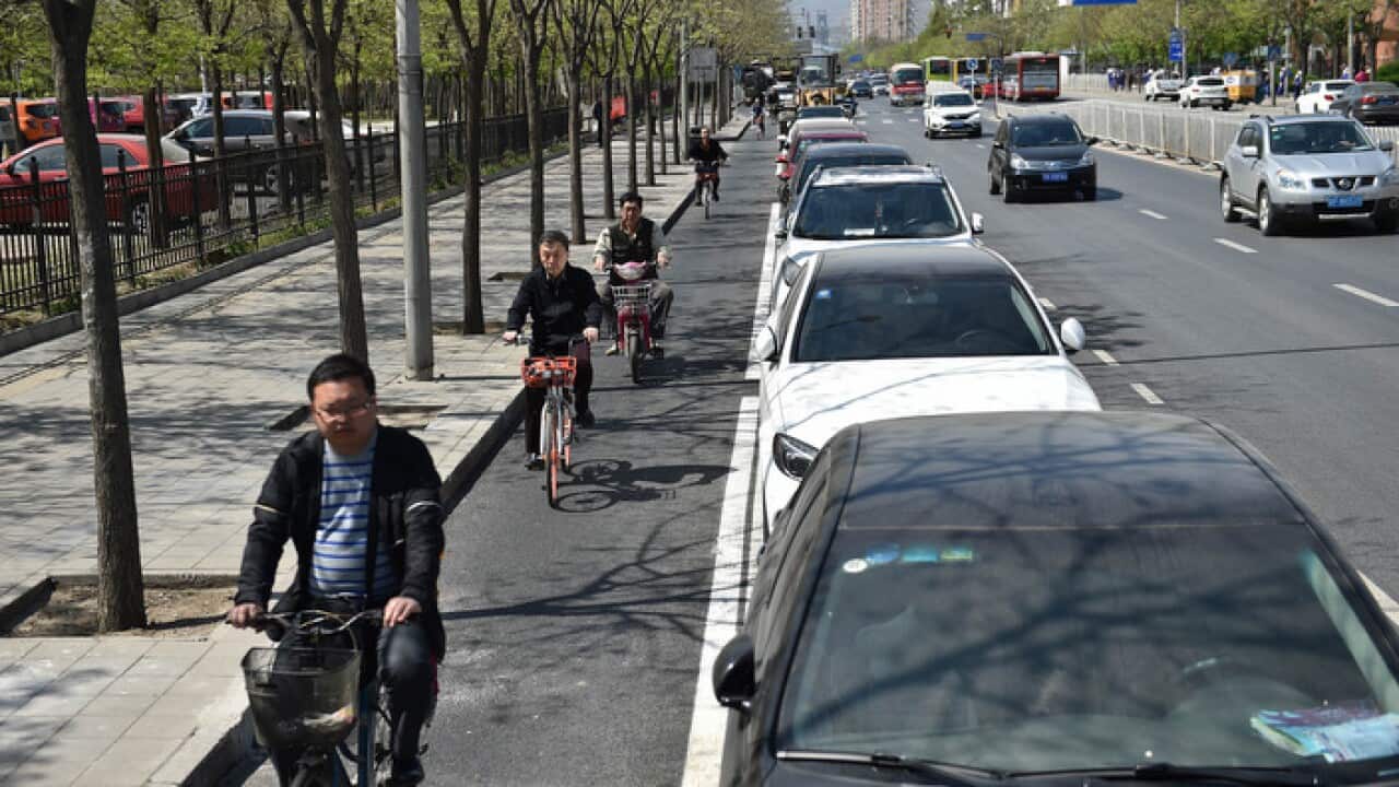 Cyclists, a parking lane and passing cars in today's Beijing (AAP)