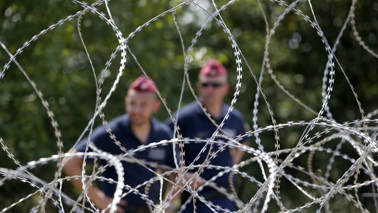 Hungarian police officers guard behind barbed wire near Morahalom, Hungary,