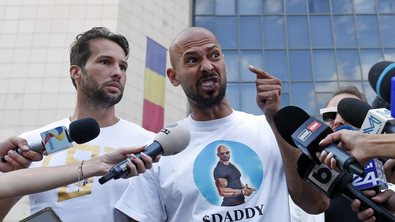 An angry man is pointing a finger and speaking to the media while another man stands by his side.