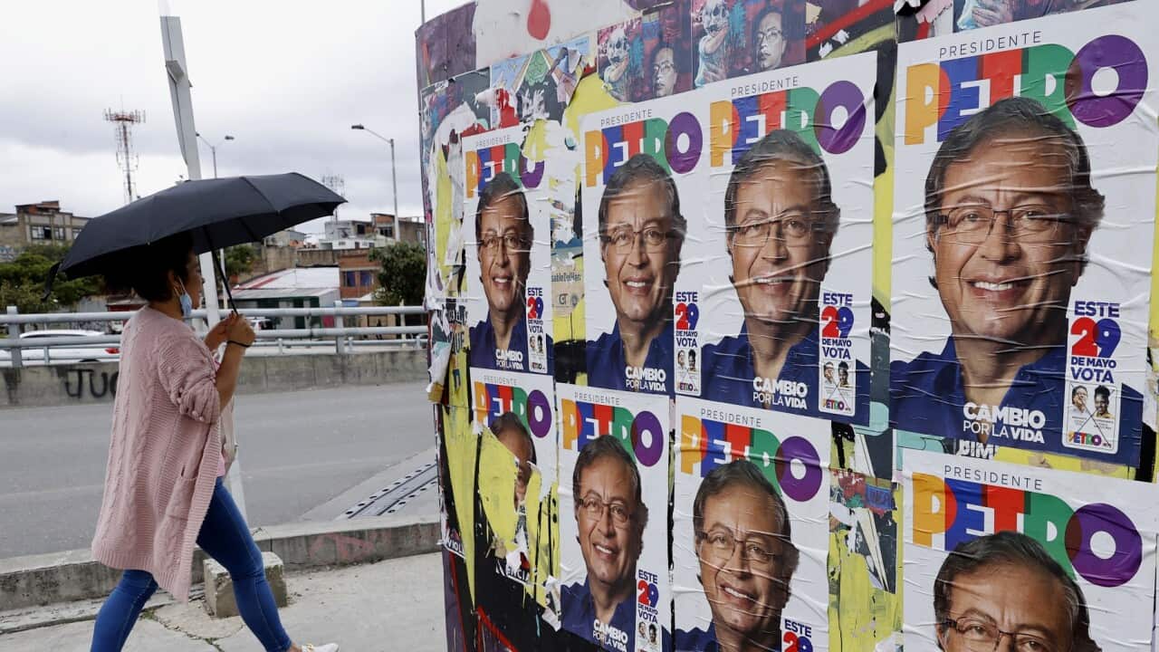 Woman walks past election posters for Colombia presidential candidate Gustavo Petro