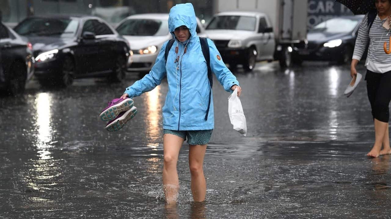 Pedestrians walk through flood waters at the corner of Clarendon and Cecil Street in South Melbourne.