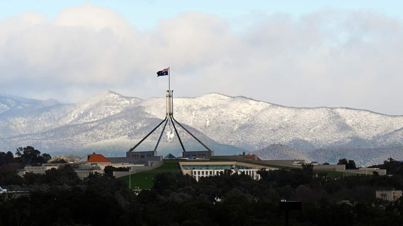 Snow covered hills are seen behind Parliament House in Canberra