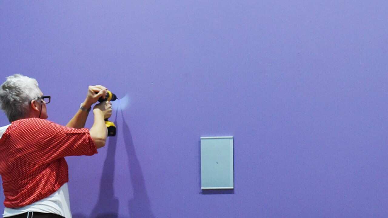 An attendant prepares to place a portrait.