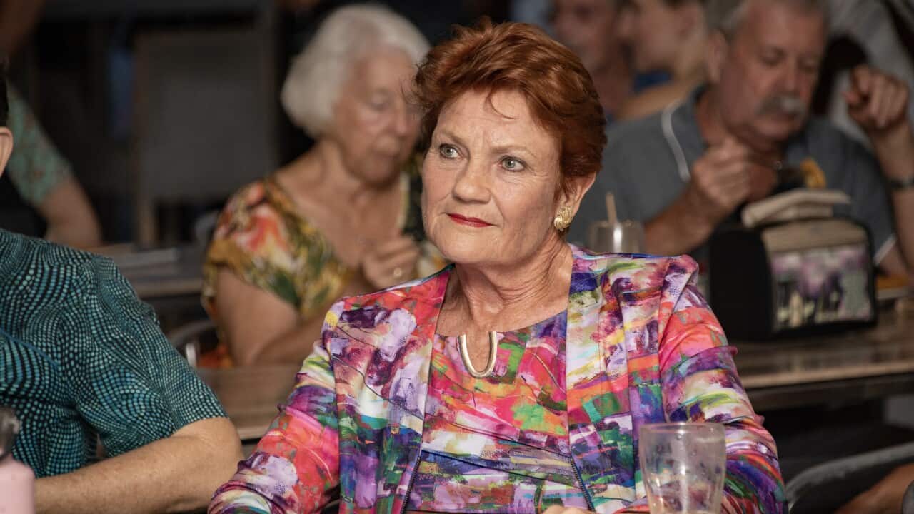 A woman wearing a colourful shirt sits at a table.