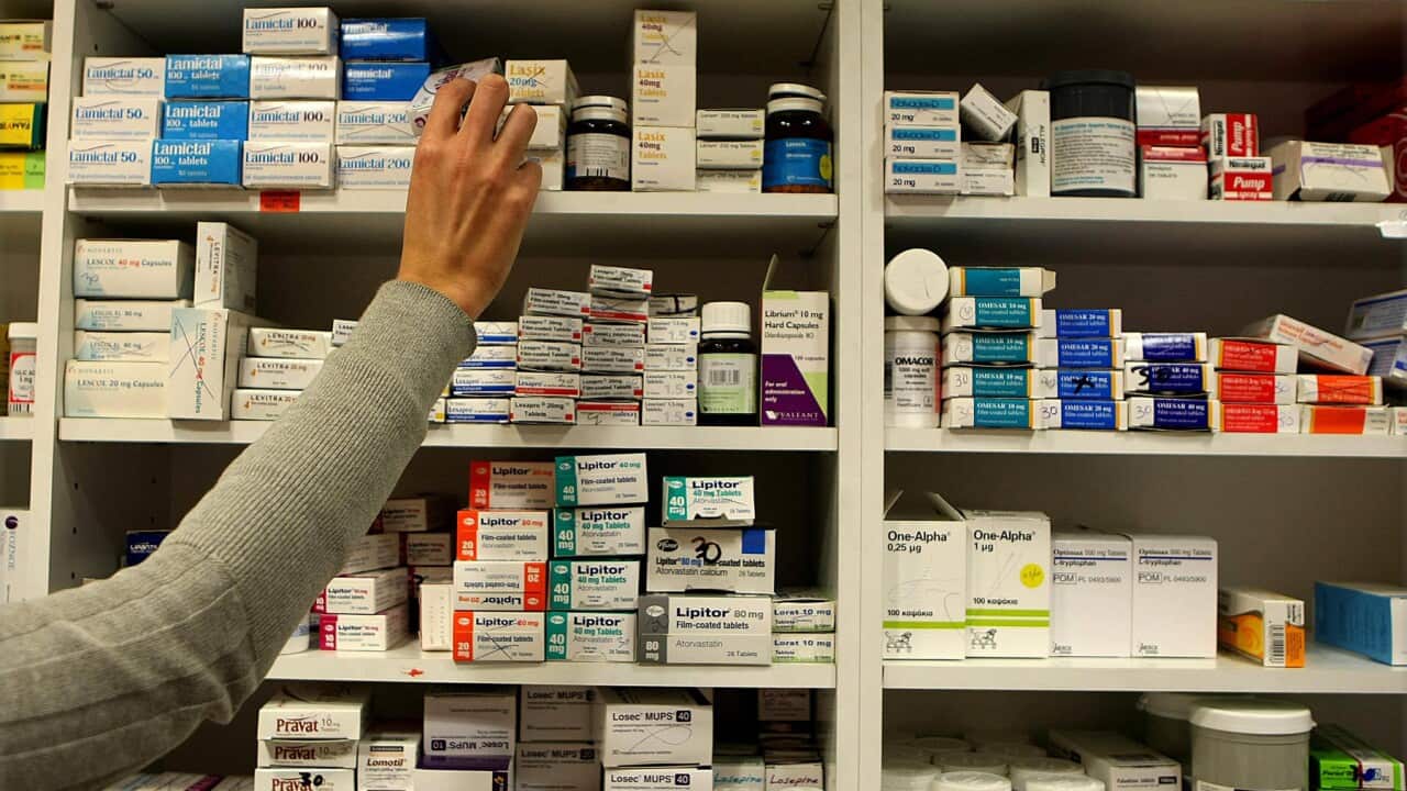 A pharmacist hand reaching for a box on medicine a shelf