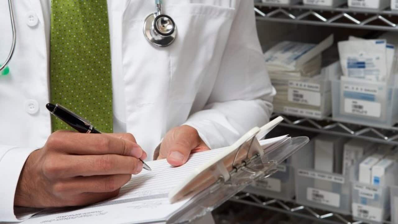 Male doctor writing in patient chart mid section