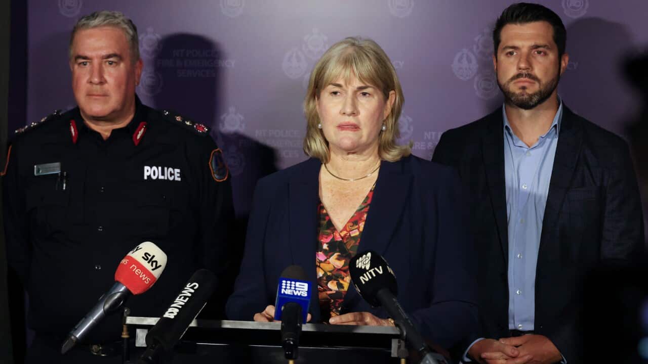 Three people speak to the media.