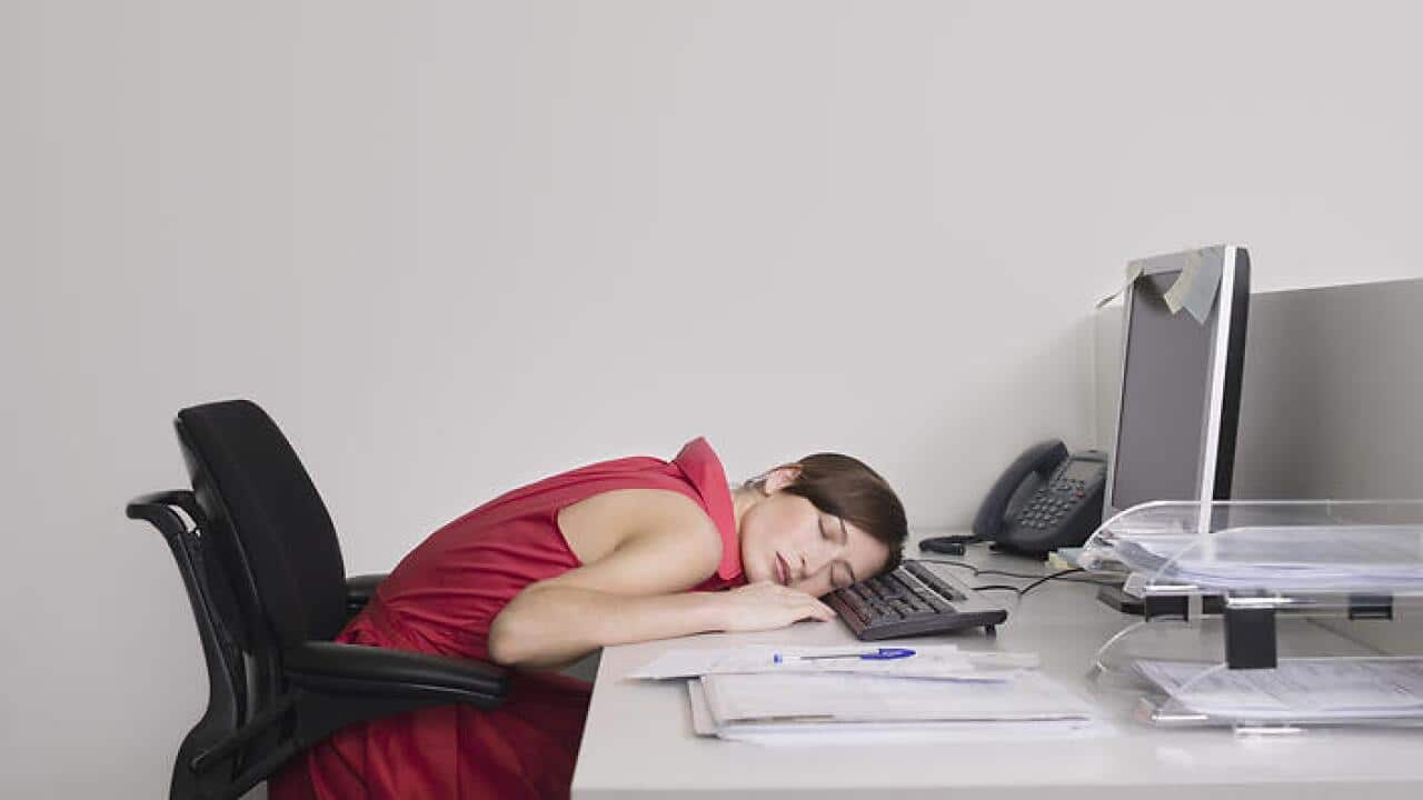 Female office worker asleep at desk in office