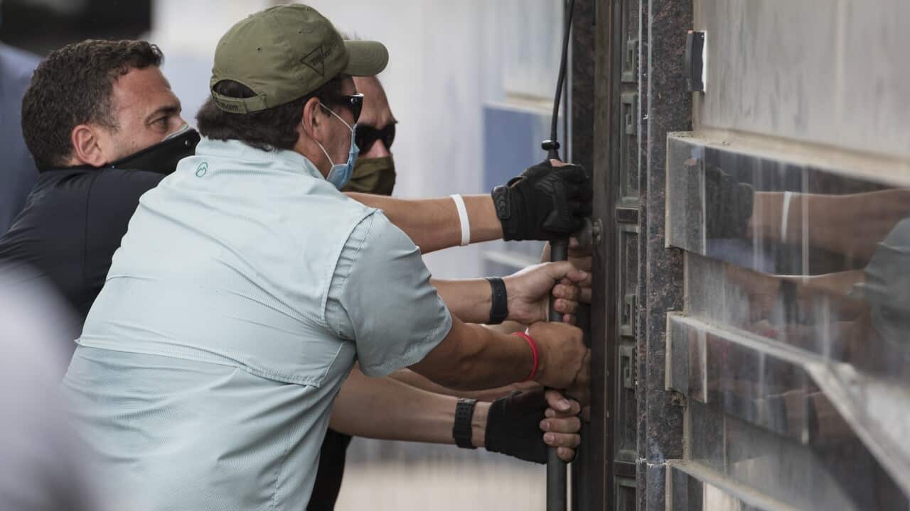Federal officials and a locksmith pull on a door to make entry into the vacated Consulate General of China building in Houston.