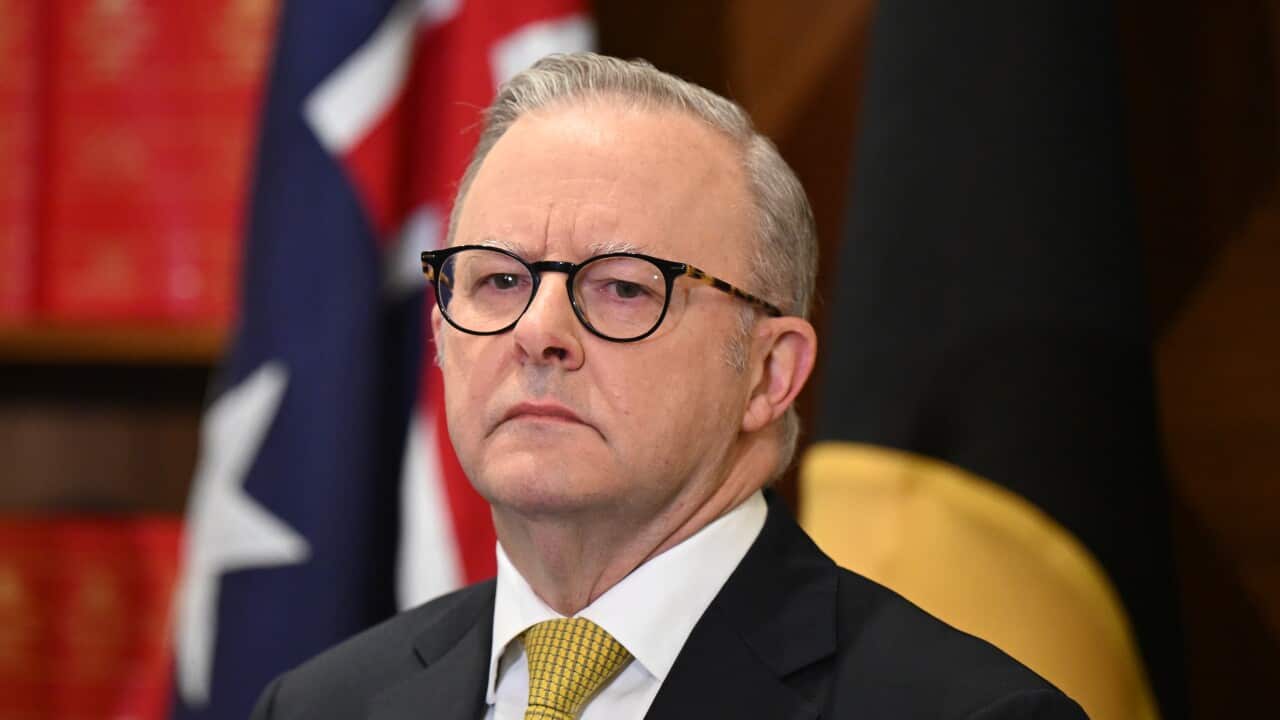 Anthony Albanese wearing a suit with a yellow tie, standing in front of Australian flat