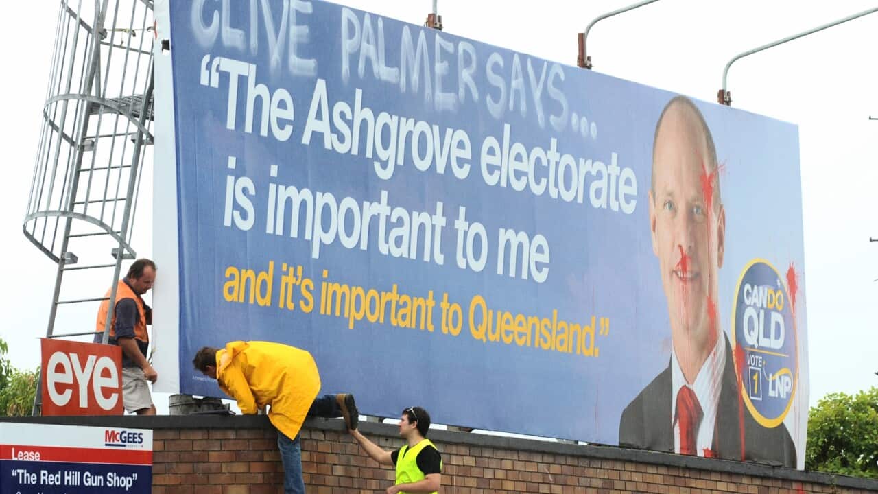 Workers inspect a defaced Liberal National Party (LNP) campaign billboard on a road leading into the Ashgrove electorate in Brisbane, Thursday, March 22, 2012.  (AAP Image/Dave Hunt) 