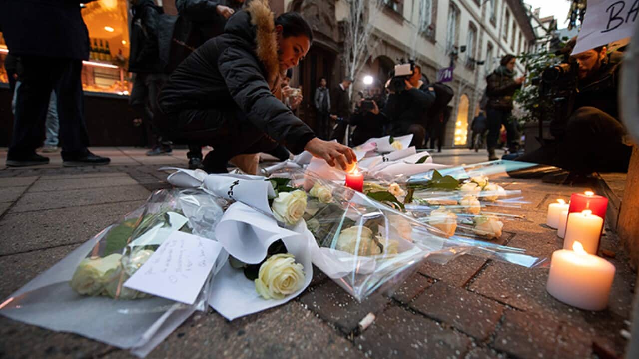 A woman lights a candle near the Strasbourg Christmas market.