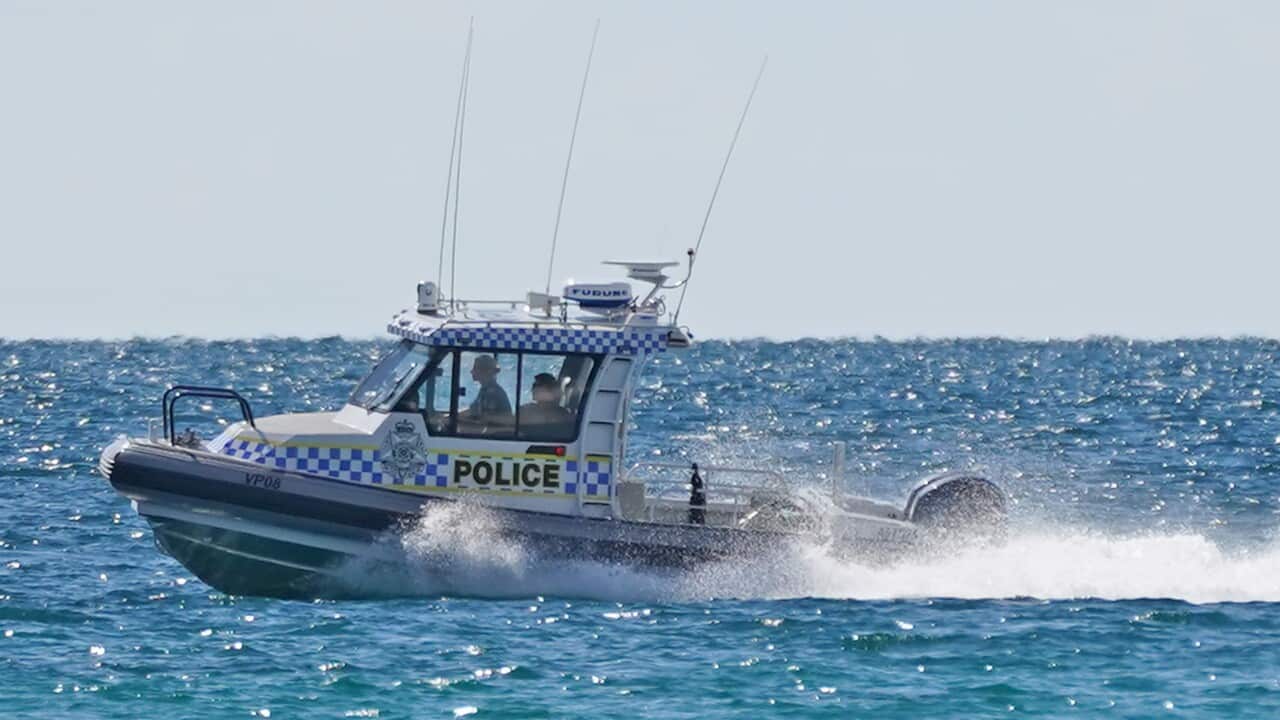 A boat speeds on the water with a police banner visible on the side