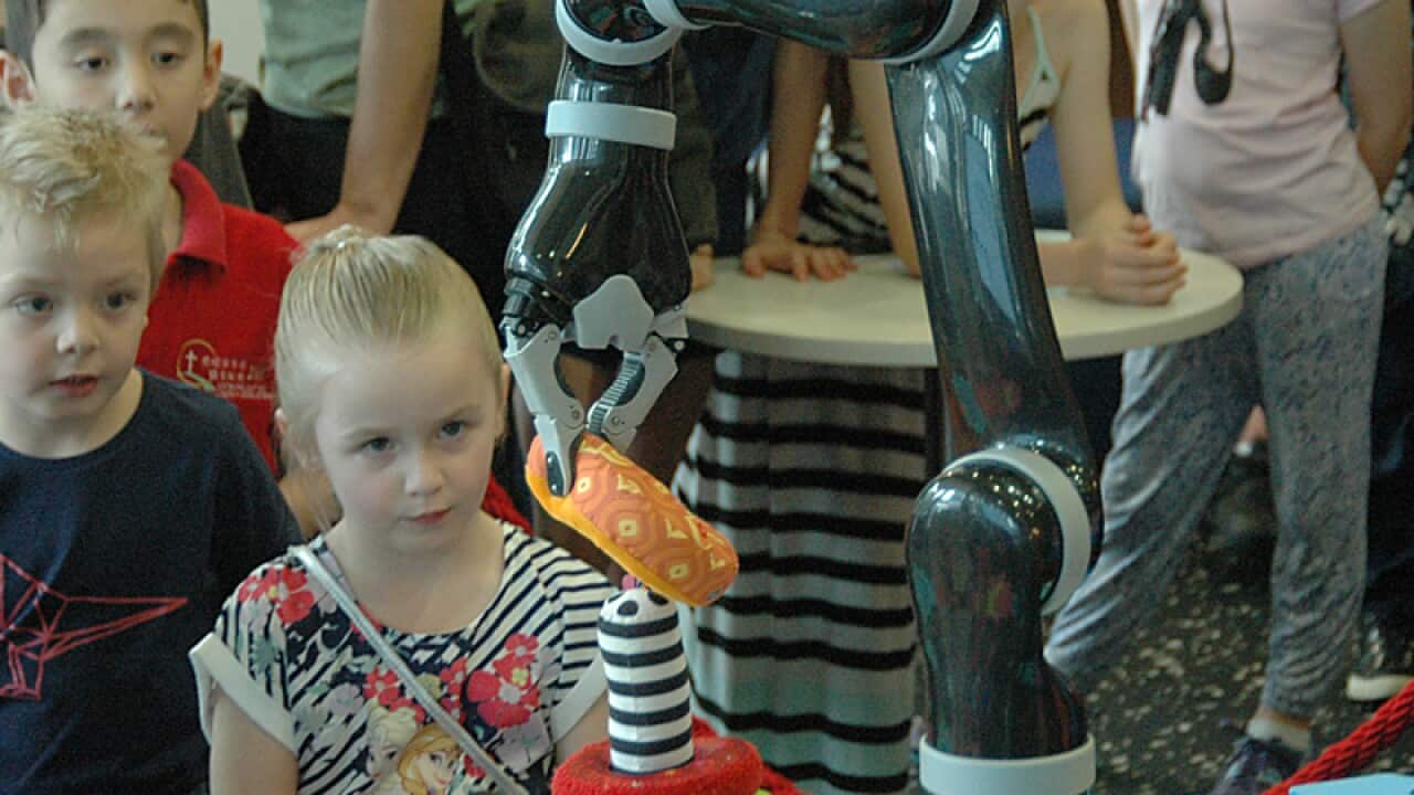 A girl tries to manoeuvre a robotic arm