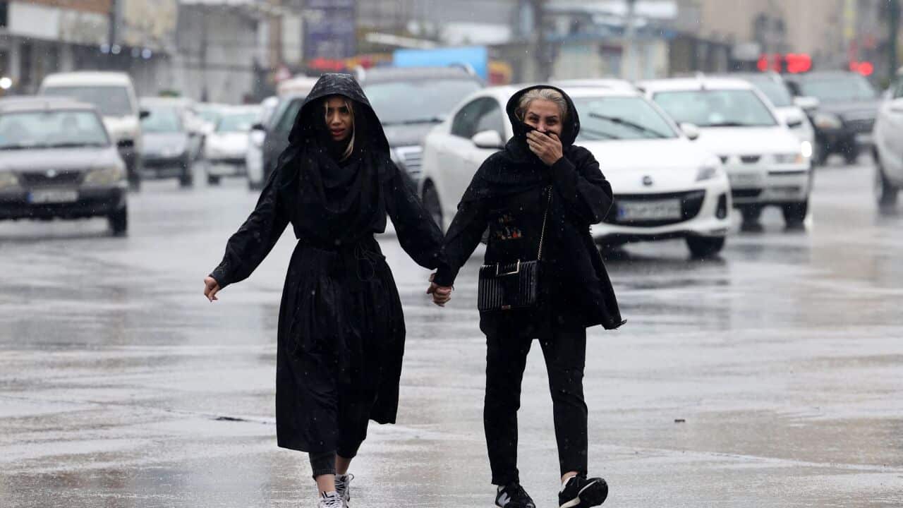 Two women holding hands walk in the street