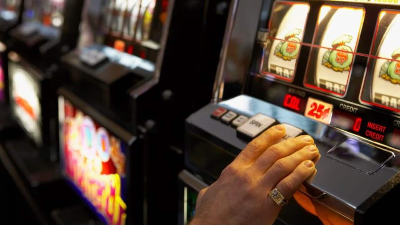 Man pushing the spin button on a slot machine