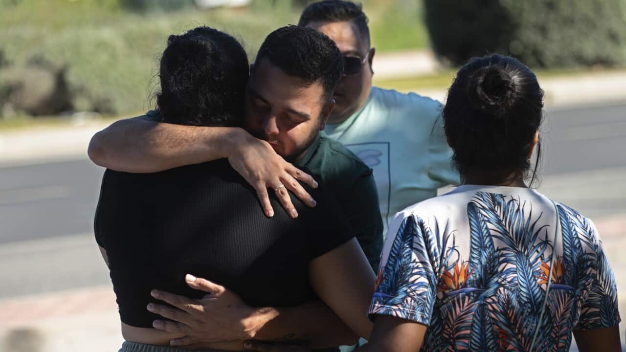 A man and a women embrace as they console one another