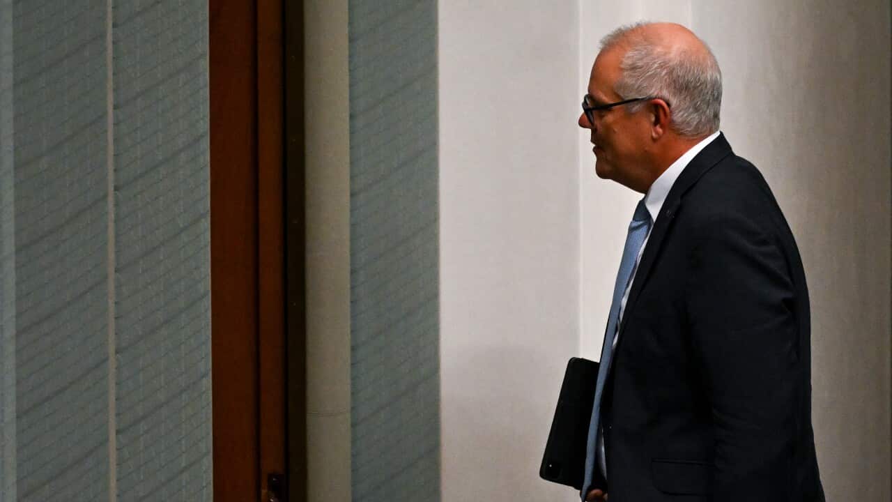 Scott Morrison walking out of a parliament chamber holding a file.