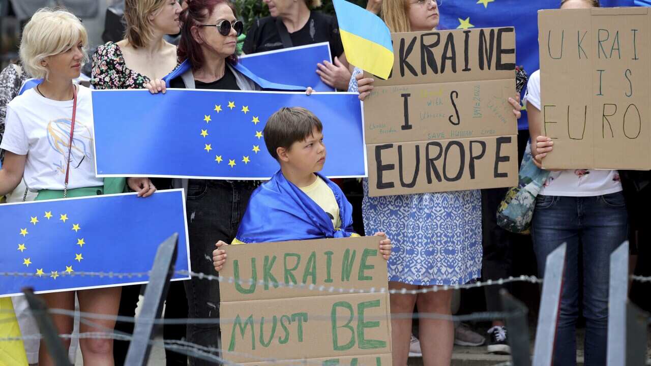 Protestors in support of Ukraine stand with signs and EU flags during a demonstration outside of an EU summit in Brussels.