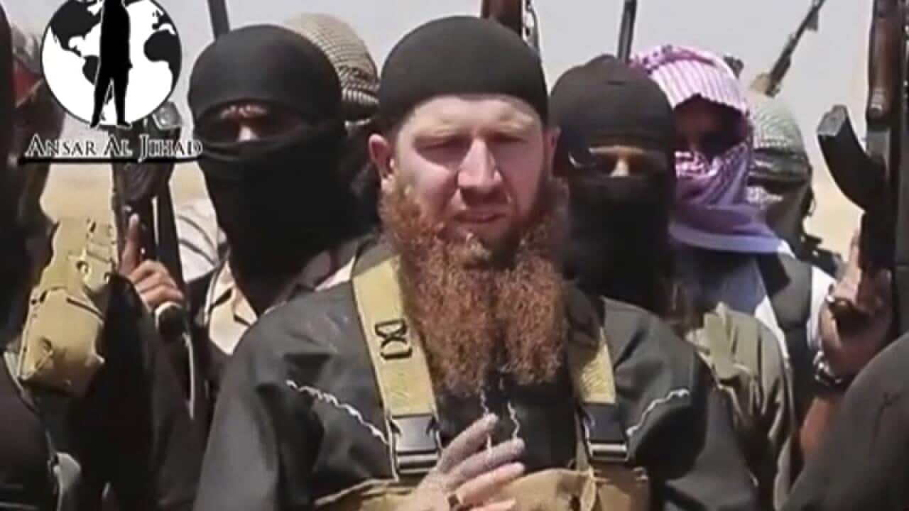 Omar al-Shishani standing next to the group's spokesman