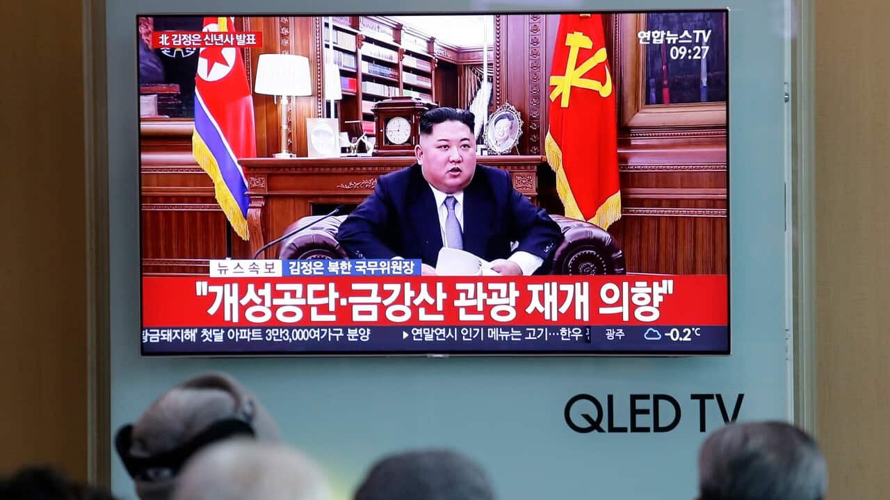 People watch a TV news on a screen showing North Korean leader Kim Jong Un delivering a New Year's speech.
