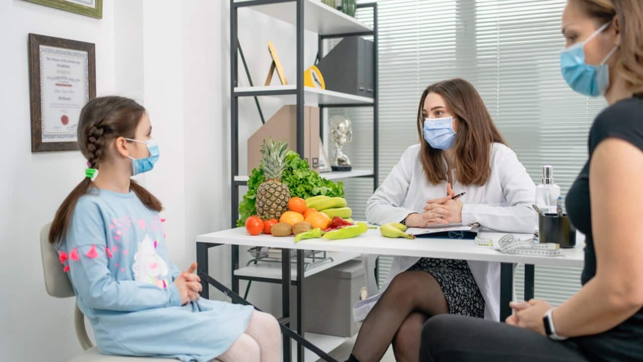dietitian holding diet plan during consultation with child patient in the office