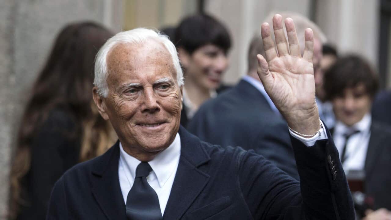 A man wearing a suit, waving.
