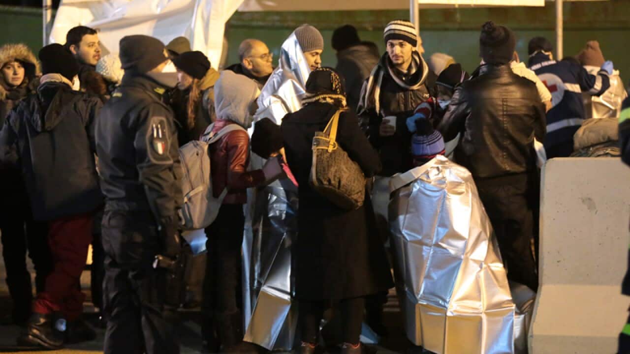 Migrants wait after disembarking from a cargo ship in Italy