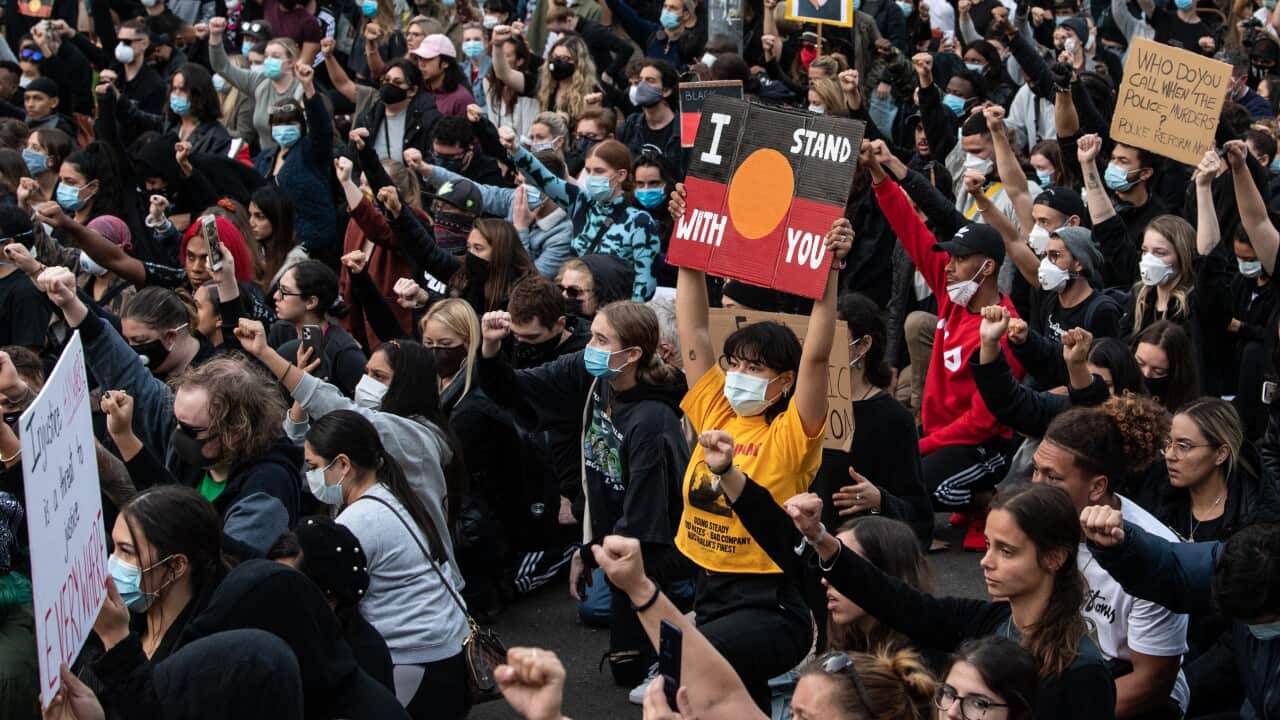 Thousands of protesters kneel and salute at a Black Lives Matter rally in Sydney.