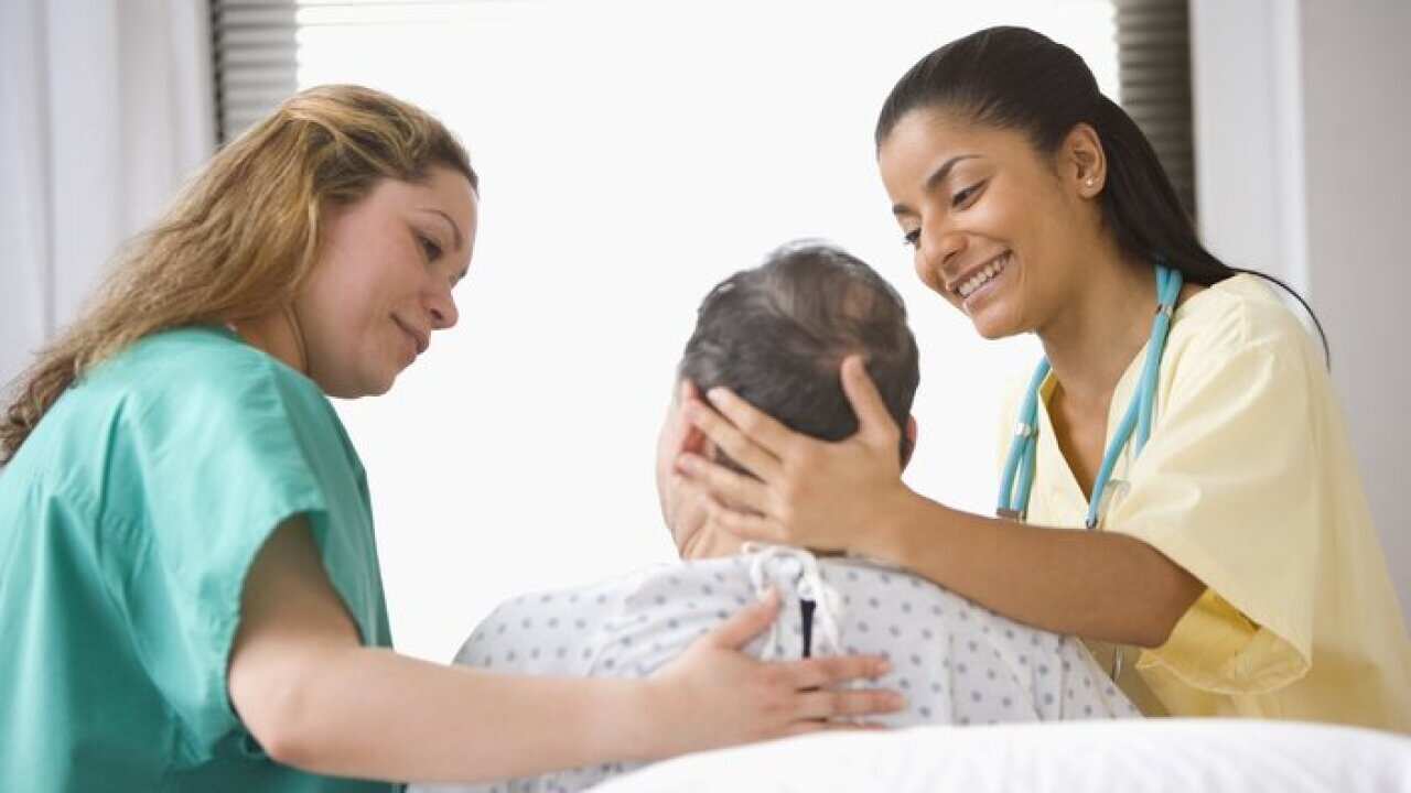 Patient being assisted by two medical assistants