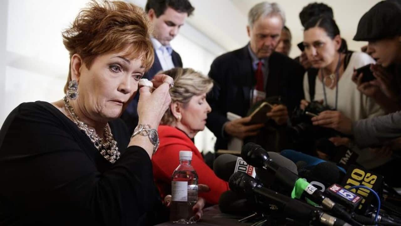 Beverly Young Nelson wipes tears as her lawyer talks to the media.