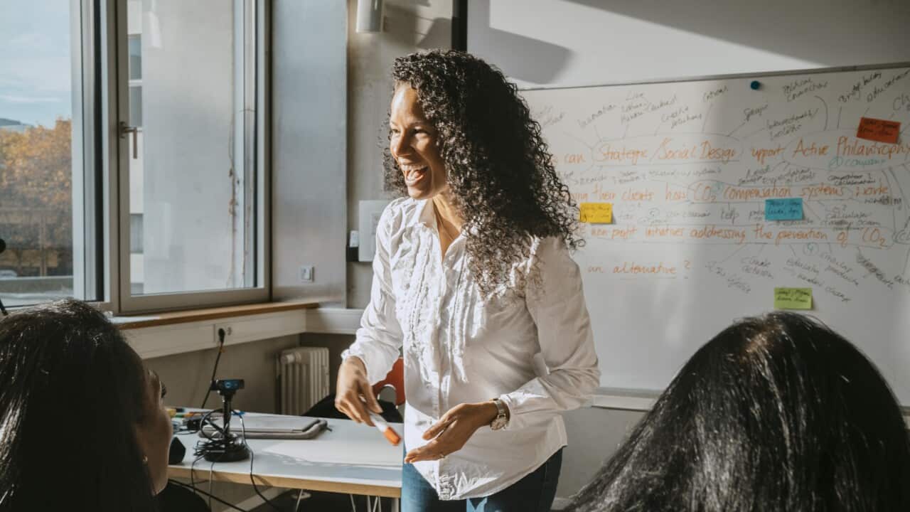 Cheerful professor teaching students sitting in classroom at community college